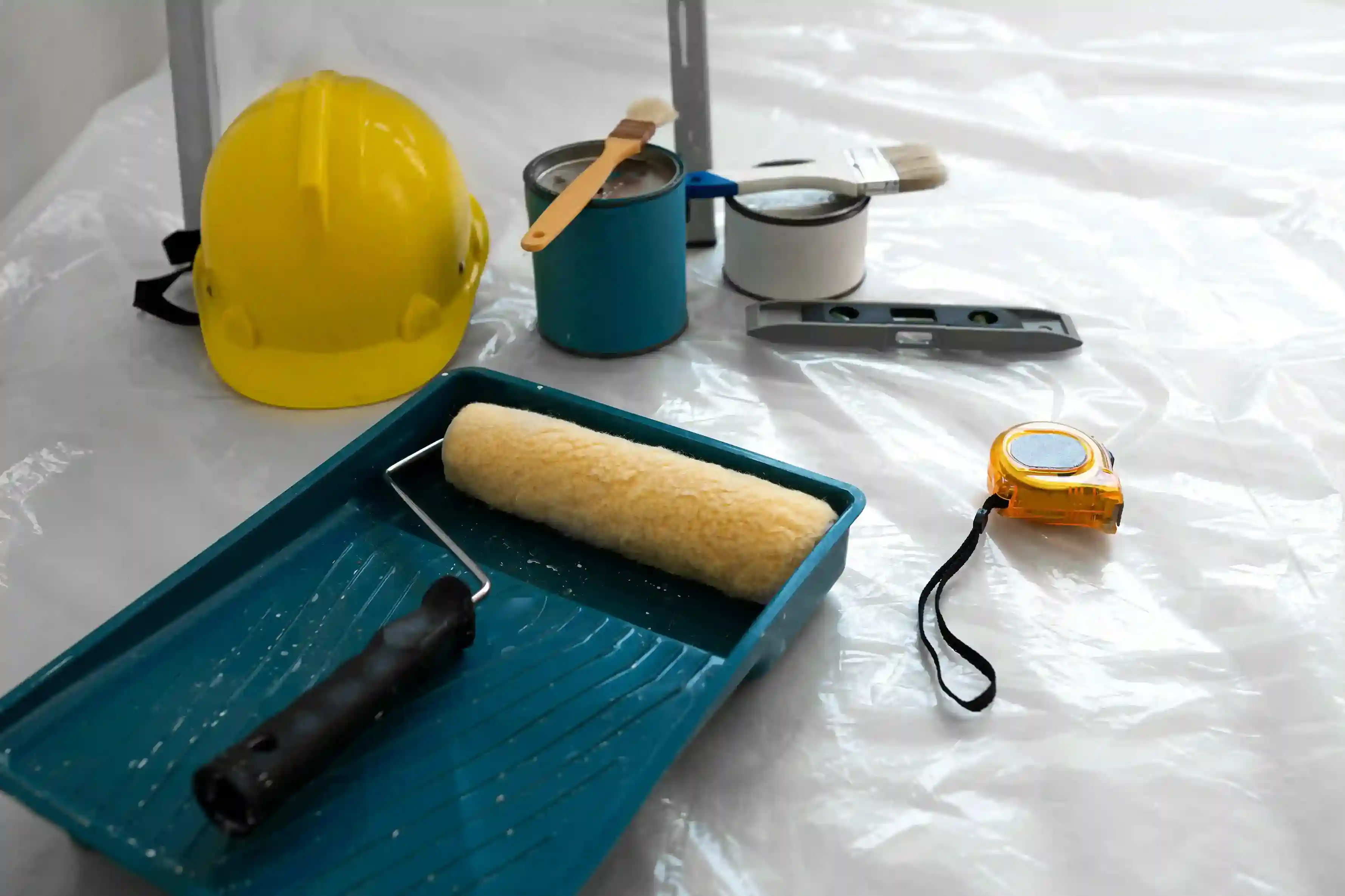 Painting tools, safety helmet, and roller tray on job site