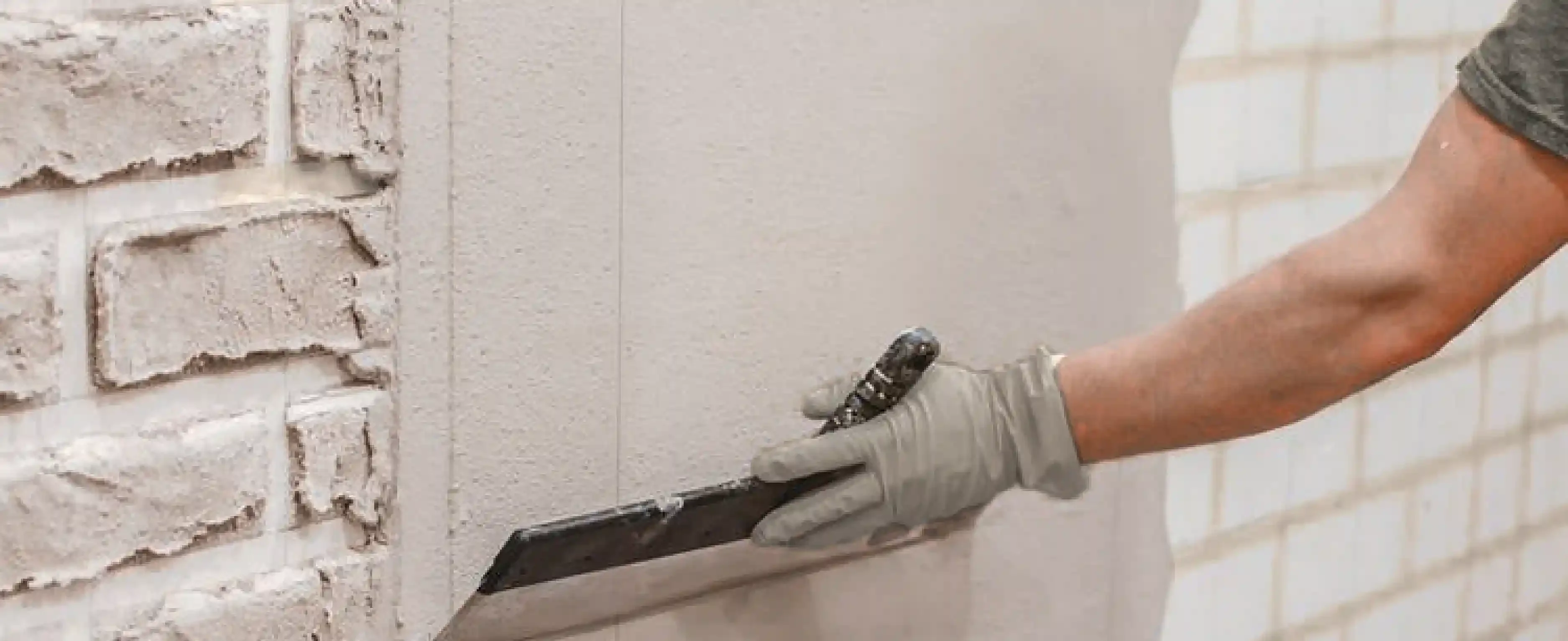 Expert applying smooth cement render on a brick wall – discover the key differences between cement render and plaster walls for stunning indoor and outdoor finishes